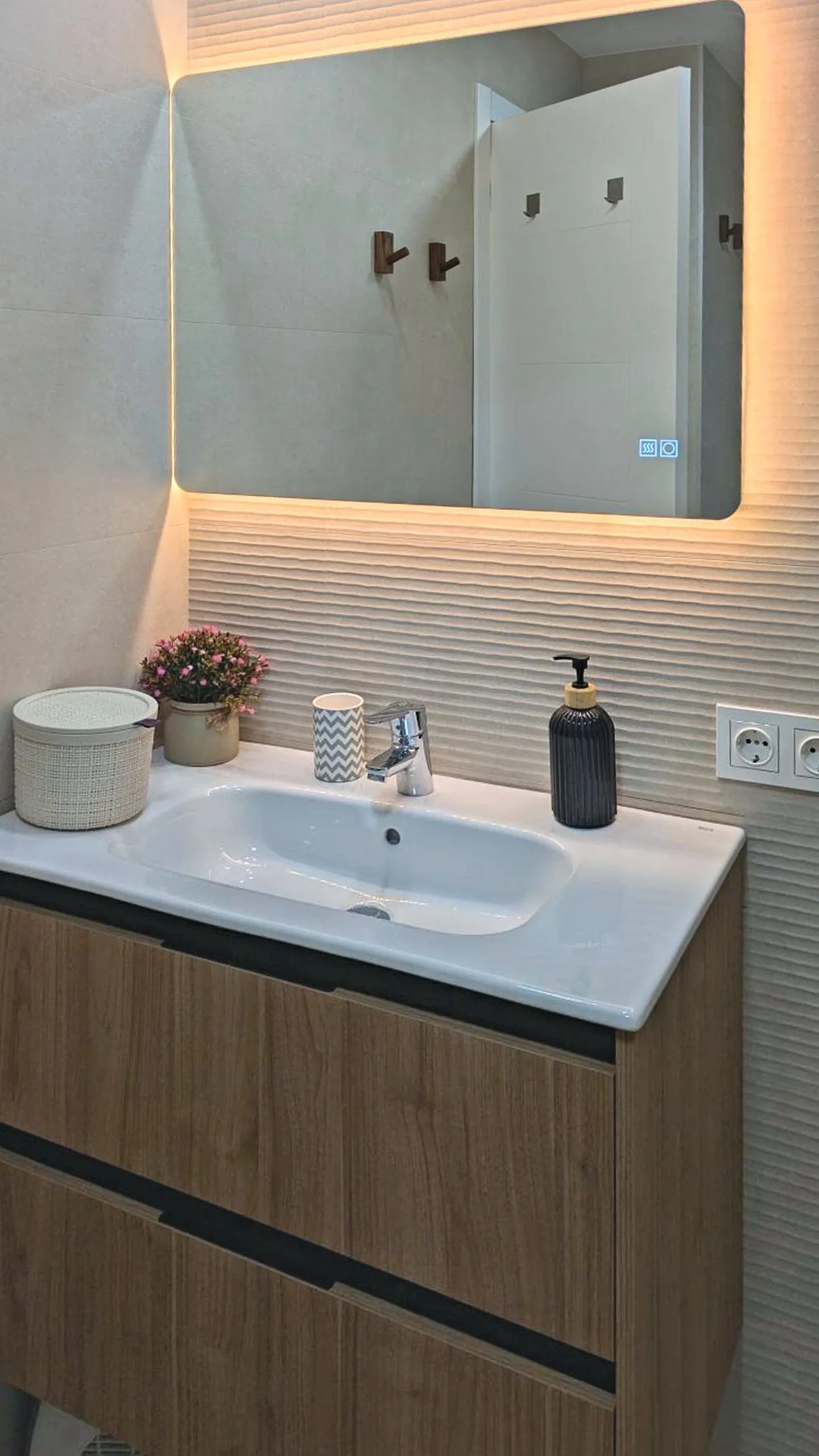 Baño reformado con mueble de madera y espejo iluminado
